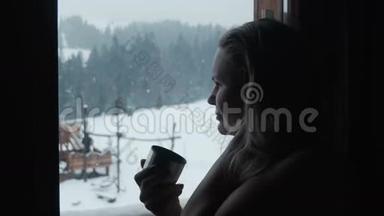 冬天，女人在度假村的窗户附近喝茶